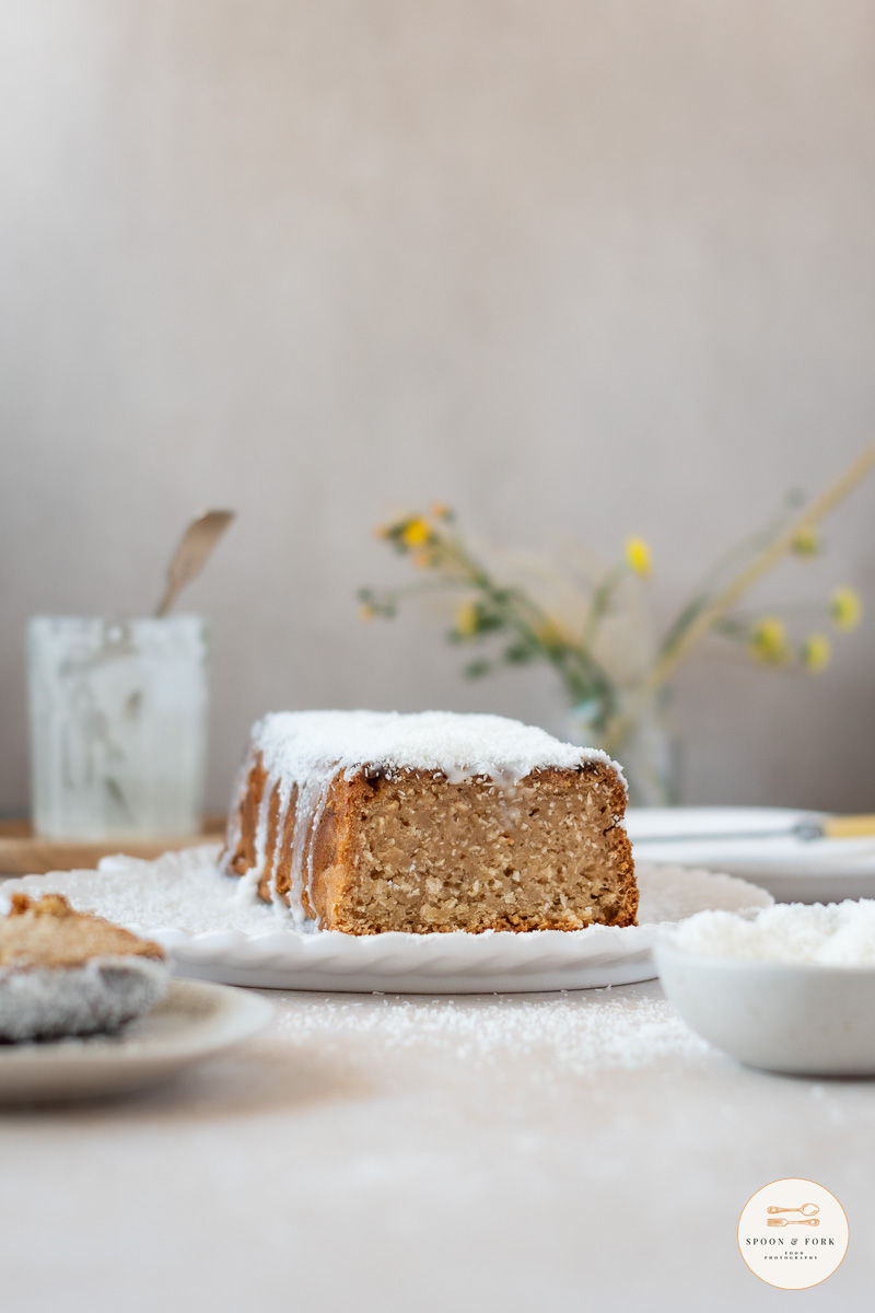 A slice of coconut loaf cake cooking a white plate.