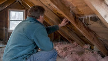 Homeowner inspecting attic ice dam damage