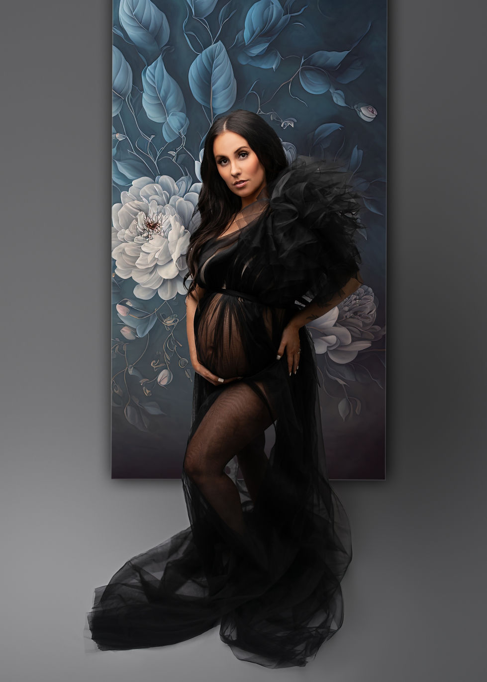 a pregnant woman in a black dress stands in front of a painting of flowers