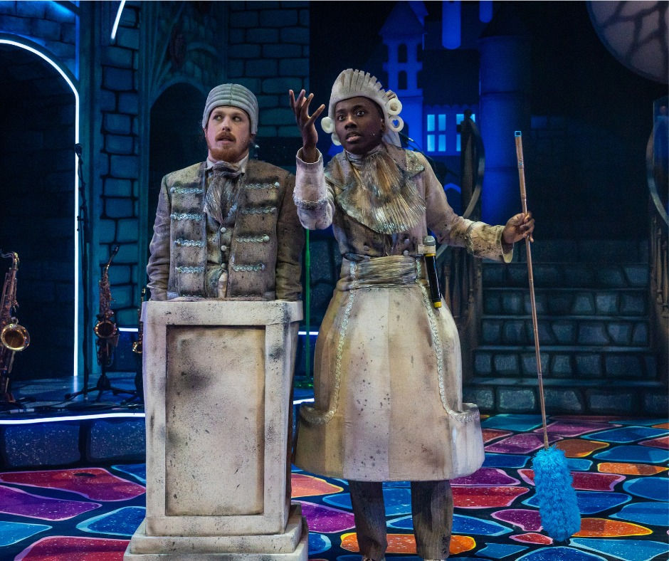 two figures on the stage, they are wearing costumds of grey that make them look like they are made of stone - one dressed as a stone column statue, the other as a stone fountain
