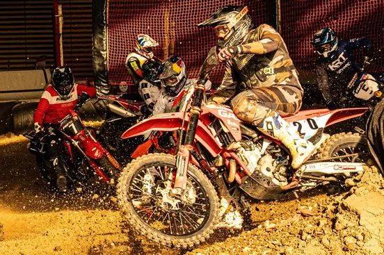 Pilotes de motocross en pleine course sur un circuit indoor.
