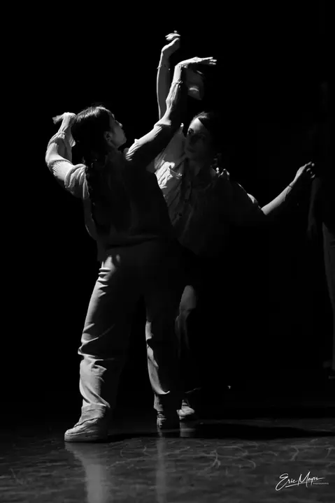 Danseurs en pleine performance sur scène photographiés en noir et blanc.
