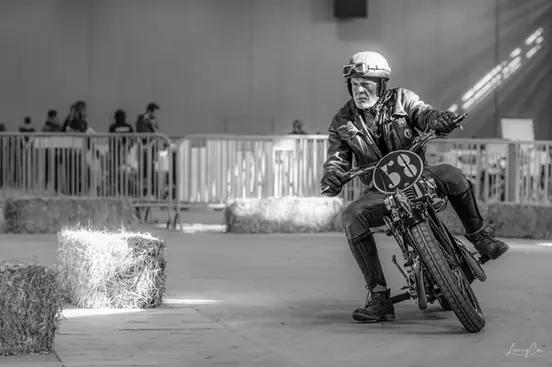 Pilote de moto ancienne engagé dans une course sur piste en intérieur.