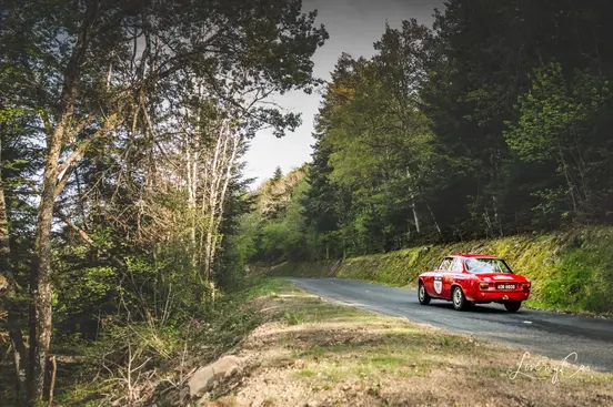 Voiture de collection photographiée sur une route lors d’un rallye automobile.