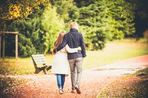 Photographie d’un couple se promenant main dans la main dans un parc lors d’une séance photo de balade amoureuse.
