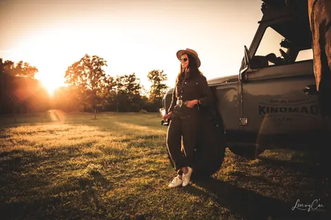 Portrait d’une participante à un événement automobile au coucher du soleil devant un véhicule tout-terrain.
