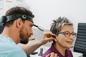 Otolaryngologist doing checkup of mid aged woman at modern medical center. Portrait of aud