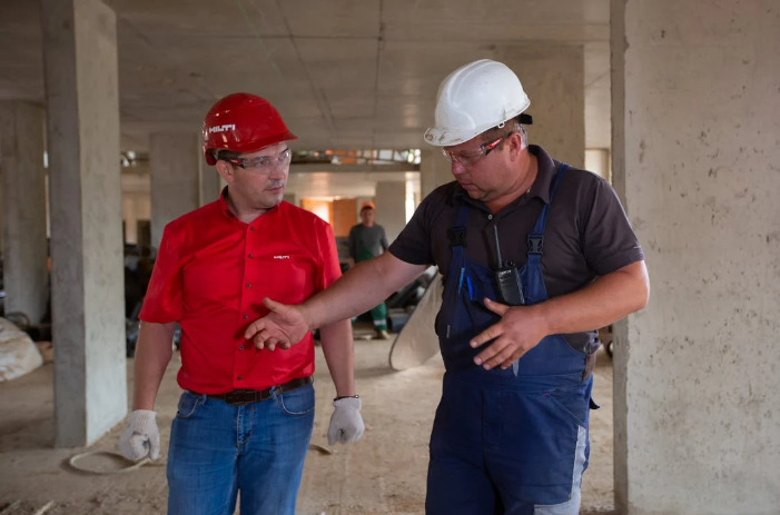 Two men in hard hats discussing an issue on a construction site.