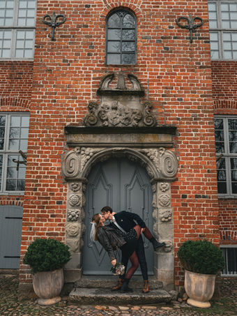 Paar küsst sich vor einem alten Backsteingebäude.