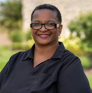 Smiling African American woman wearing glasses poses outside, Hardon Education.