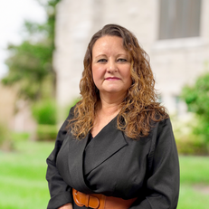 Woman with brown hair in a black blazer smiling outside. Hardon Education