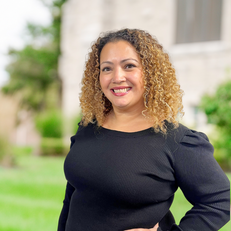 Smiling woman with curly hair, wearing black top, posing, a background ABOUT Hardon Education