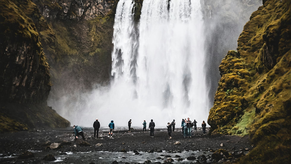 Man in raincoat standing in front of Skogafoss Waterfall