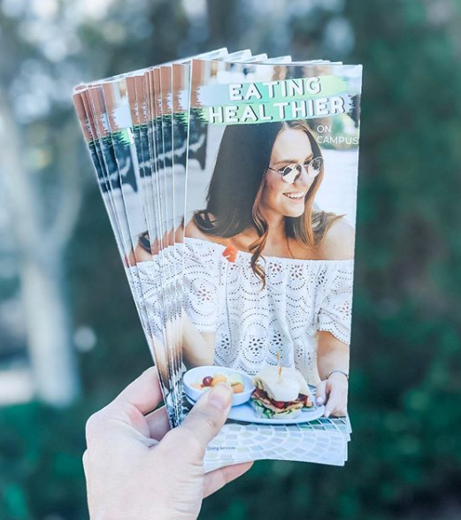 hand holds several pamphlets with a woman on the front that read "eating healthier"