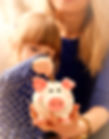 Child little girl arm putting pin money coins into happy pink faced piglet slot closeup Ma