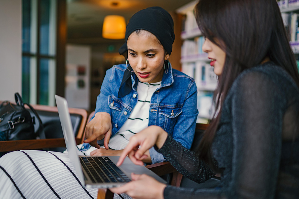 2 women working collaboratively on a laptop