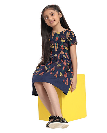 A navy blue dress adorned with vibrant, colorful patterns of leaves and flowers. Showcasing the dress's fit and style.