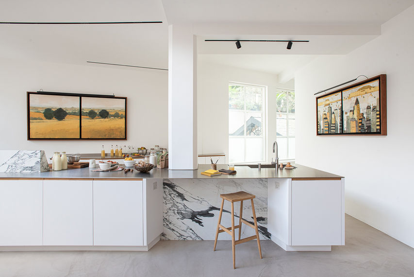 Bespoke kitchen by Jack Trench Design with Glacier White Corian worktops, European Oak cabinetry, brushed stainless island, and marble wedge splashback.