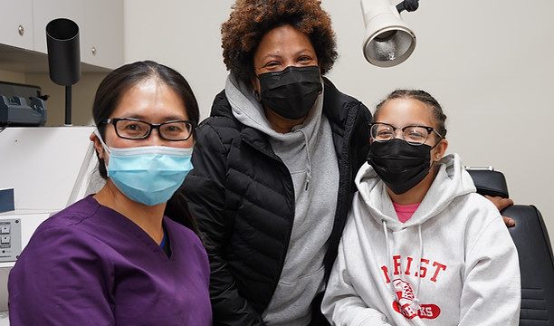 Medical professional with a woman and child, all wearing masks in a clinic