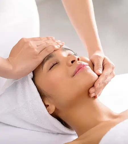 A woman smiles whilst receiving a facial