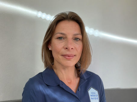 A woman in a navy polo shirt which says 'Abbey Mobile Physio'