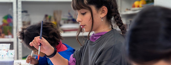 Imagen de un grupo de adolescentes sentados en caballetes y trabajando en sus pinturas en una clase de dibujo y pintura para jóvenes. La escuela de arte ofrece clases de dibujo y pintura para todas las edades, desde niños hasta adultos