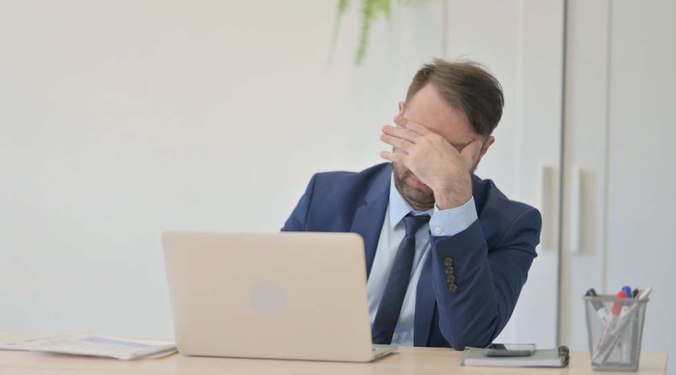 Stressed businessman with head in hand after a data loss incident. Protect your business from costly downtime with Arkansas data backup & recovery solutions.