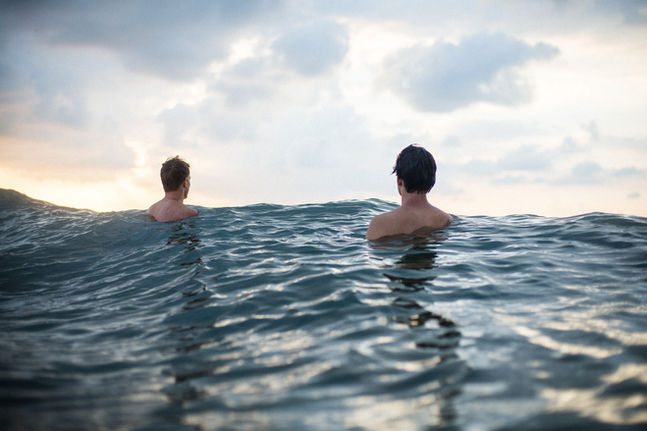 twee jonge mannen in water van achteren gezien.