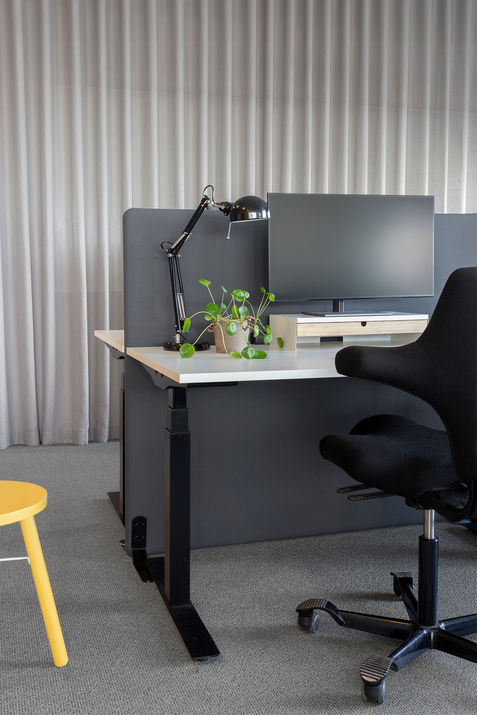 Kontorsplats med beige gardiner i bakgrunden