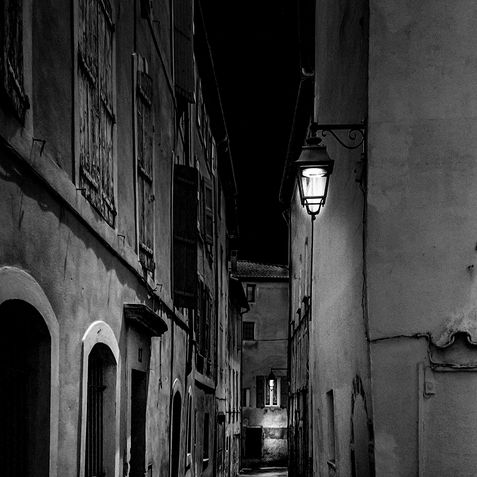 Black and white photo of an old street at night.