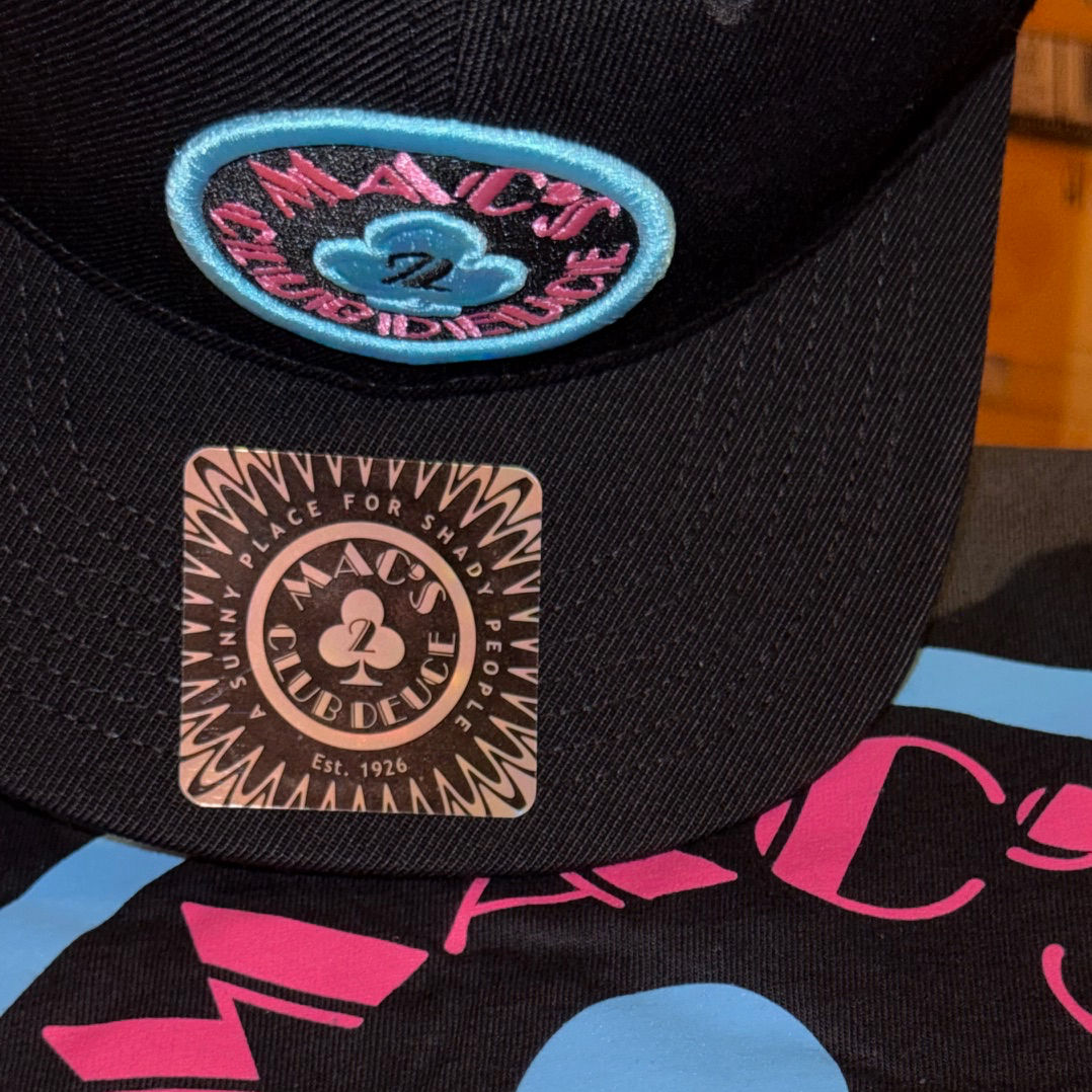 Close-up of the Mac's Club Deuce logo in Miami Vice pink and blue on a snapback baseball cap.