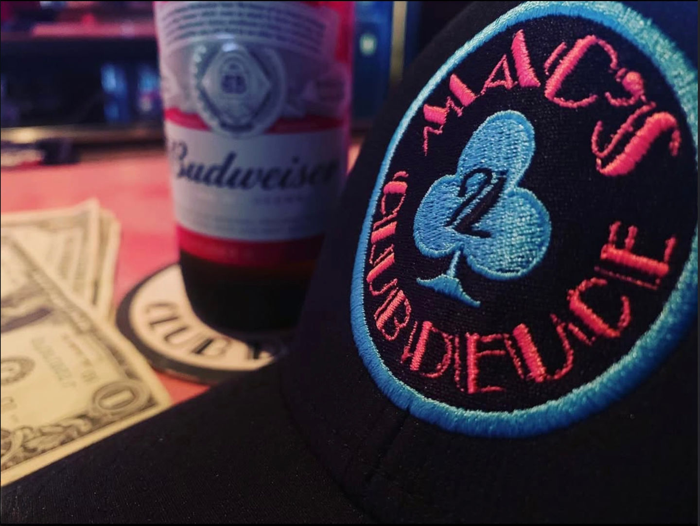 Close-up of the Mac's Club Deuce logo in Miami Vice pink and blue on a snapback baseball cap.