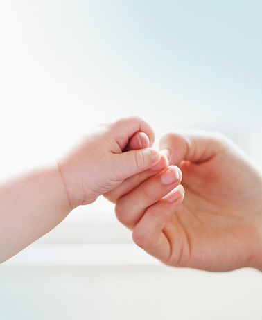 Nanny holding a baby’s hand, symbolizing trust and professional caregiver-family partnership.
