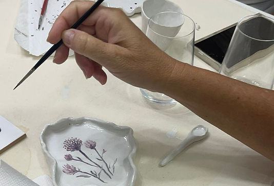 imagem de uma mão pintando uma porcelana artesanal feita no ateliê essencia vida e arte_ed