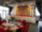 Restaurant with red chair covers and off-white color table covers.