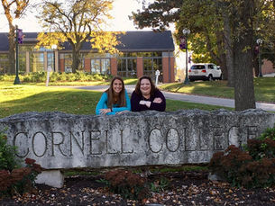 Two women posing by the stone sign in front of Cornell College