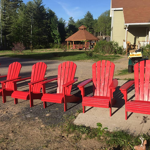 5 painted red adirondack chairs sitting in a driveway