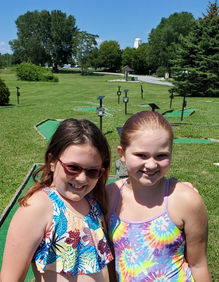 Two girls smiling at a miniature golf course