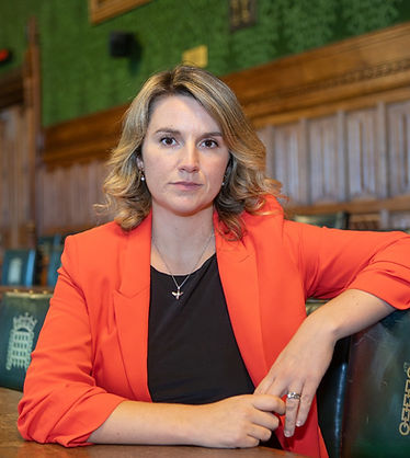 Jess sitting in parliament orange blazer serious (2).jpg