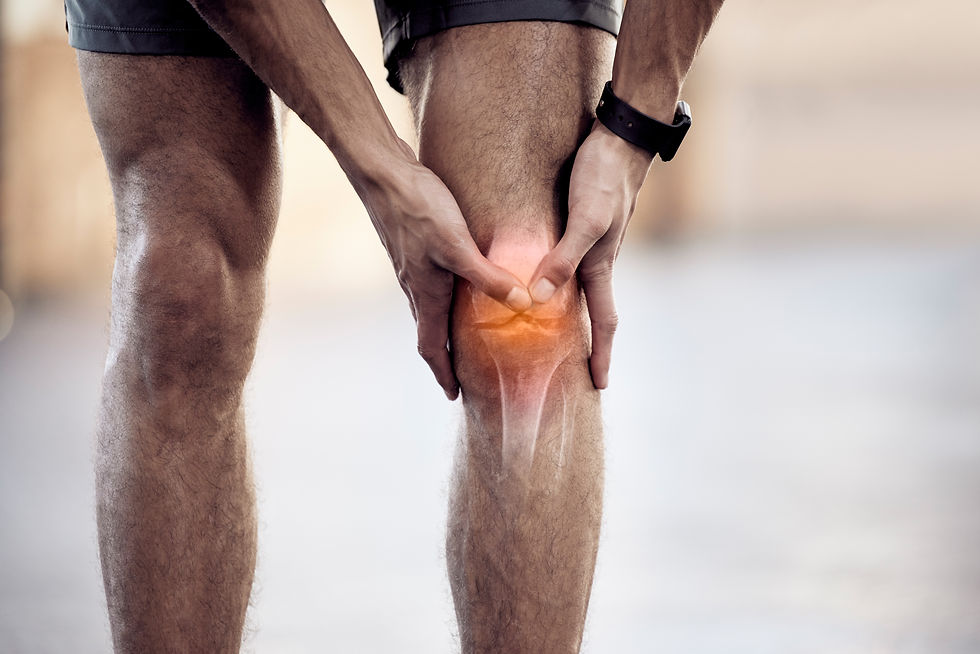 Man holding a painful knee, orange glow highlighting the joint, with athletic shorts and a fitness tracker in a soft indoor setting.