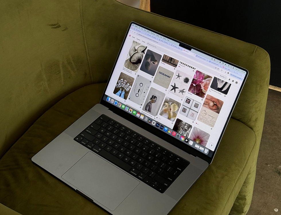 Pinterest feed open on a laptop on a green couch