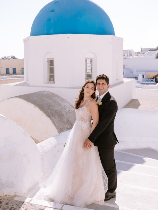 Bride and groom pose together in Santorini with blue roof, wedding day. Mysite