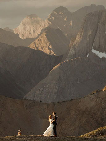Couple embraces with stunning mountain range backdrop during wedding ceremony. Mysite
