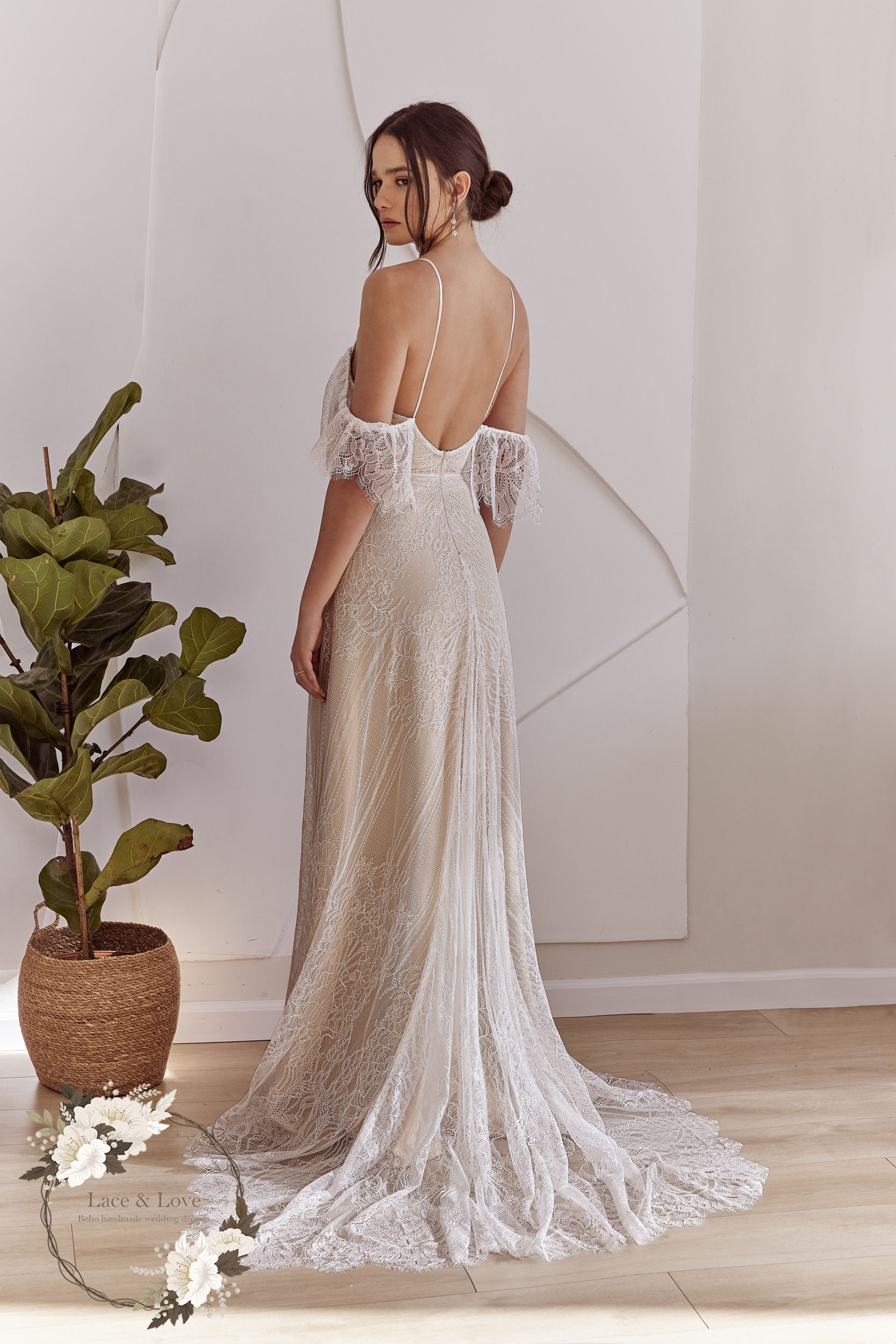 אישה בשמלת תחרה רומנטית ומרשימה עומדת ליד עציץ shany sasson hebrew