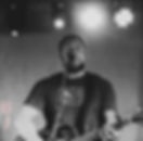Musician singing and playing acoustic guitar at a live music event.