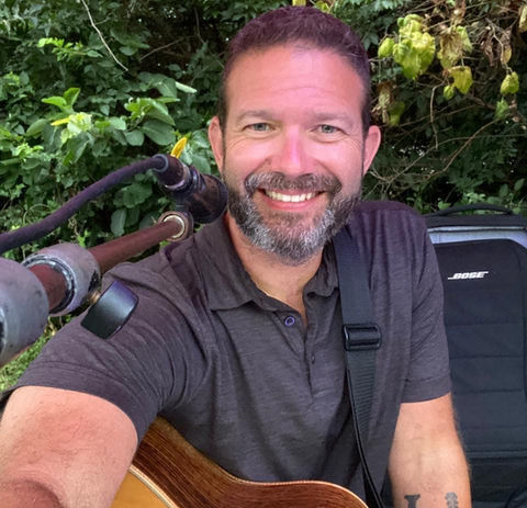 Smiling man with beard playing acoustic guitar