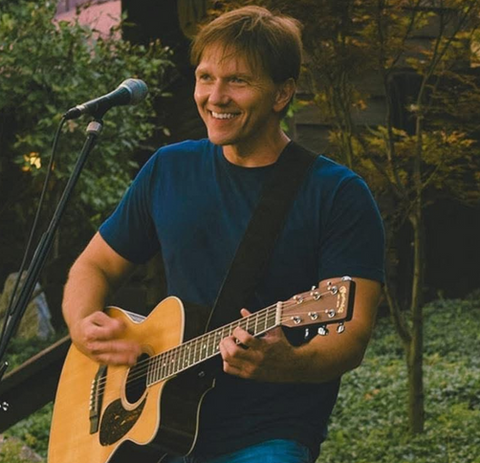 Smiling man playing acoustic guitar, singing