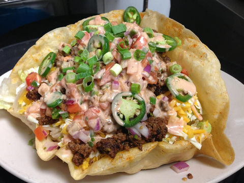 Large taco salad with ground beef, cheese, and jalapeños in a bowl.