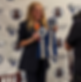Woman holding two blue ribbons, smiling at an event with "Chanticleer Reviews" backdrop. Ribbons read "First Place" and "Grand Prize".