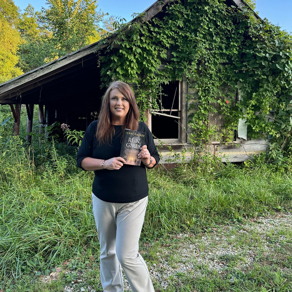 Jenny Cafaro with her novel standing in front of abandoned cabin